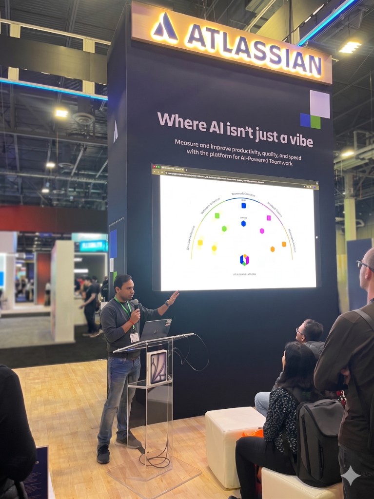 Dushyant Sharma presenting at the Atlassian booth at AWS re:Invent 2025 in Las Vegas, with the “Where AI isn’t just a vibe” keynote slide and Teamwork Graph diagram behind him.